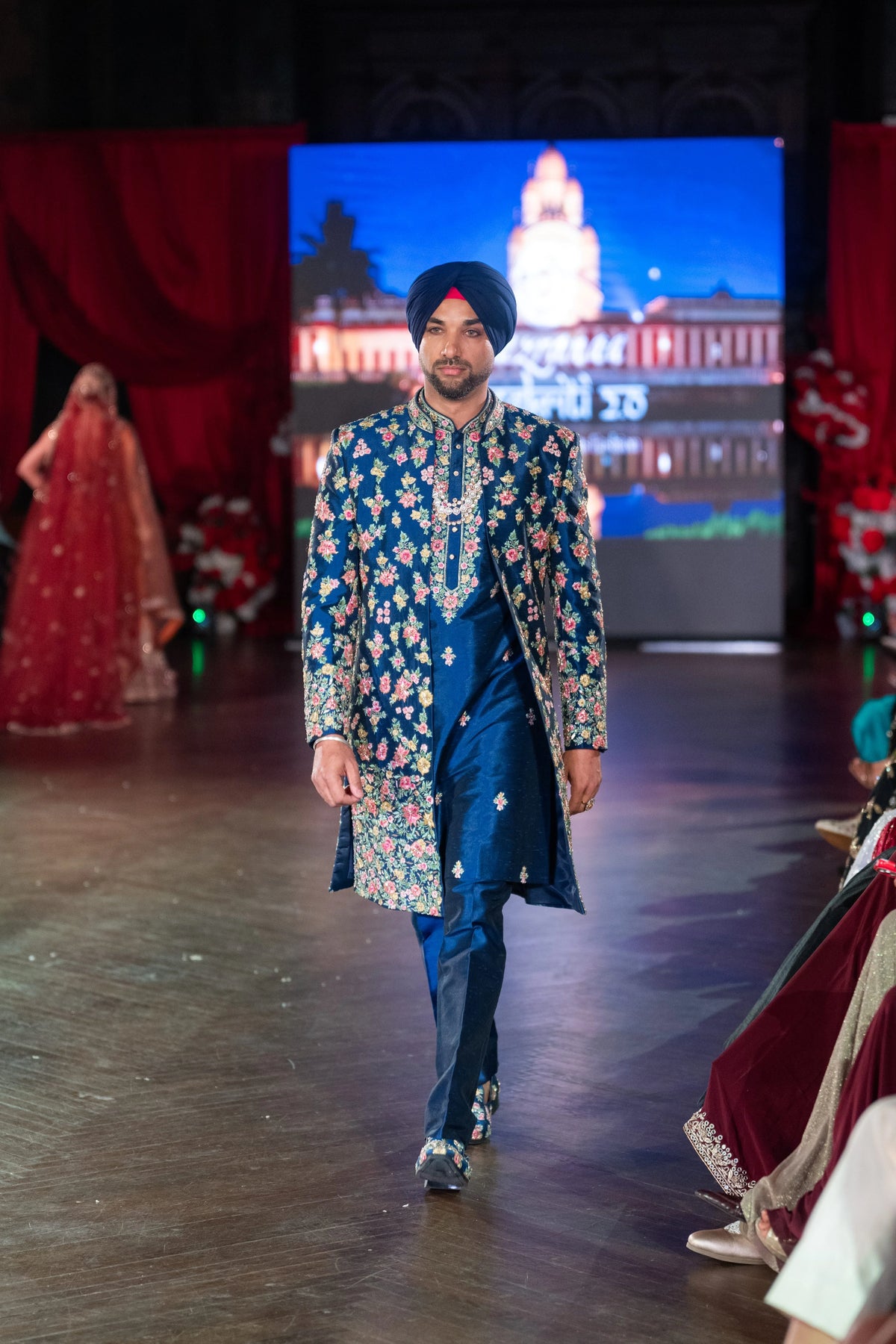 Front view of the Raas Leela embroidered blue sherwani and fitted trousers, turbaned model stepping forward