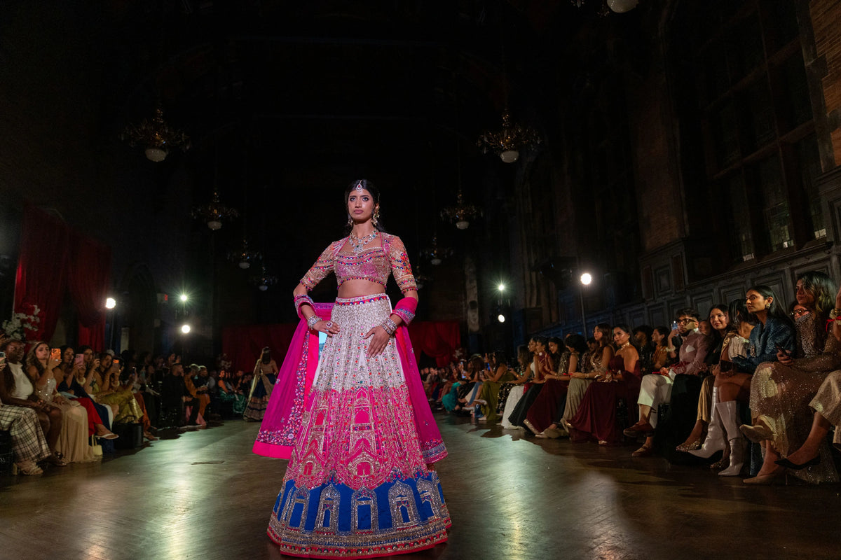Distant runway view of the Banke Bihari Holi pink, ivory and blue lehenga with the magenta dupatta