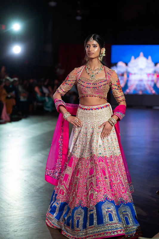 Banke Bihari Holi pink and ivory lehenga with a blue temple-arch border and magenta dupatta on the runway