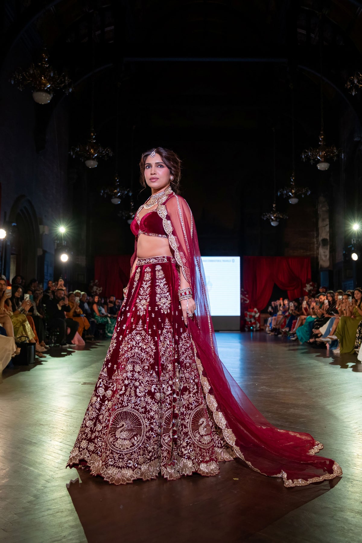 Side view of the Belur Math maroon velvet lehenga with gold zari embroidery and red net train