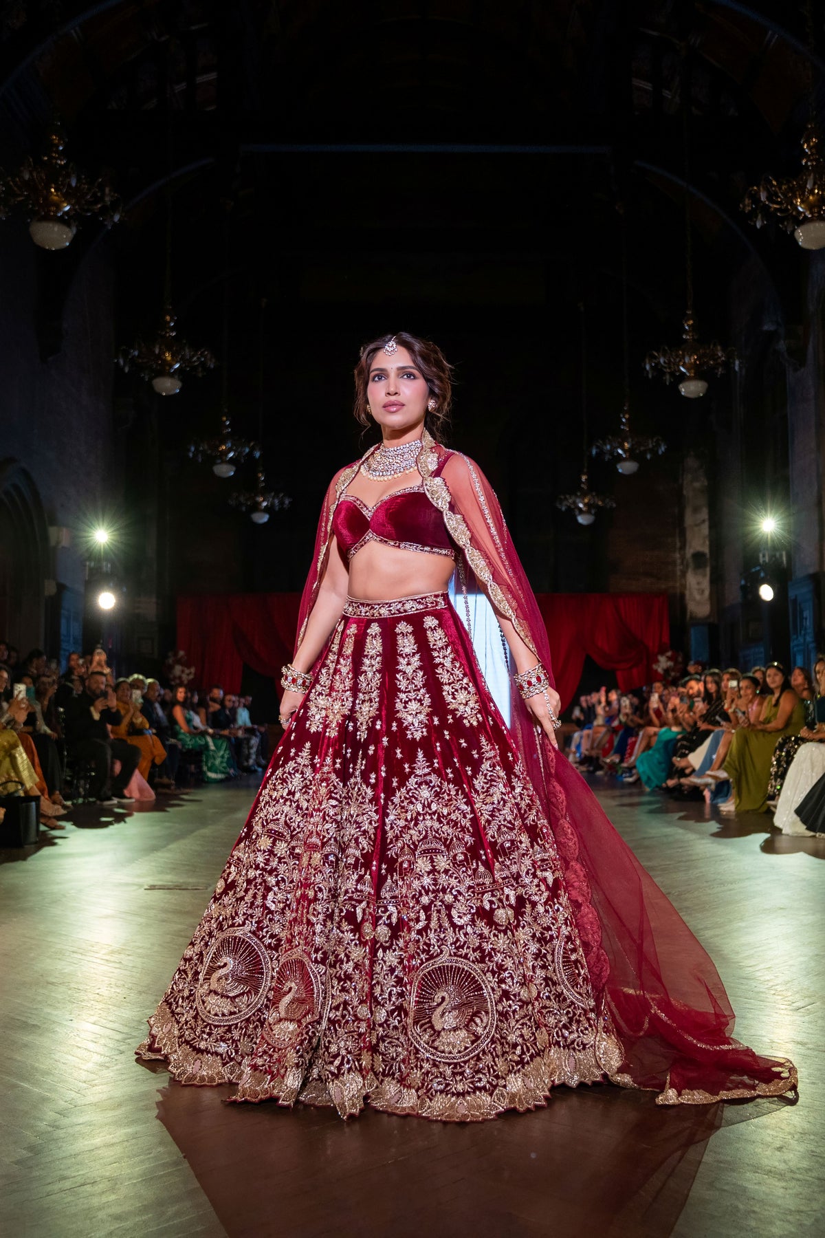 Belur Math maroon velvet lehenga with a long red net train, model walking toward the audience