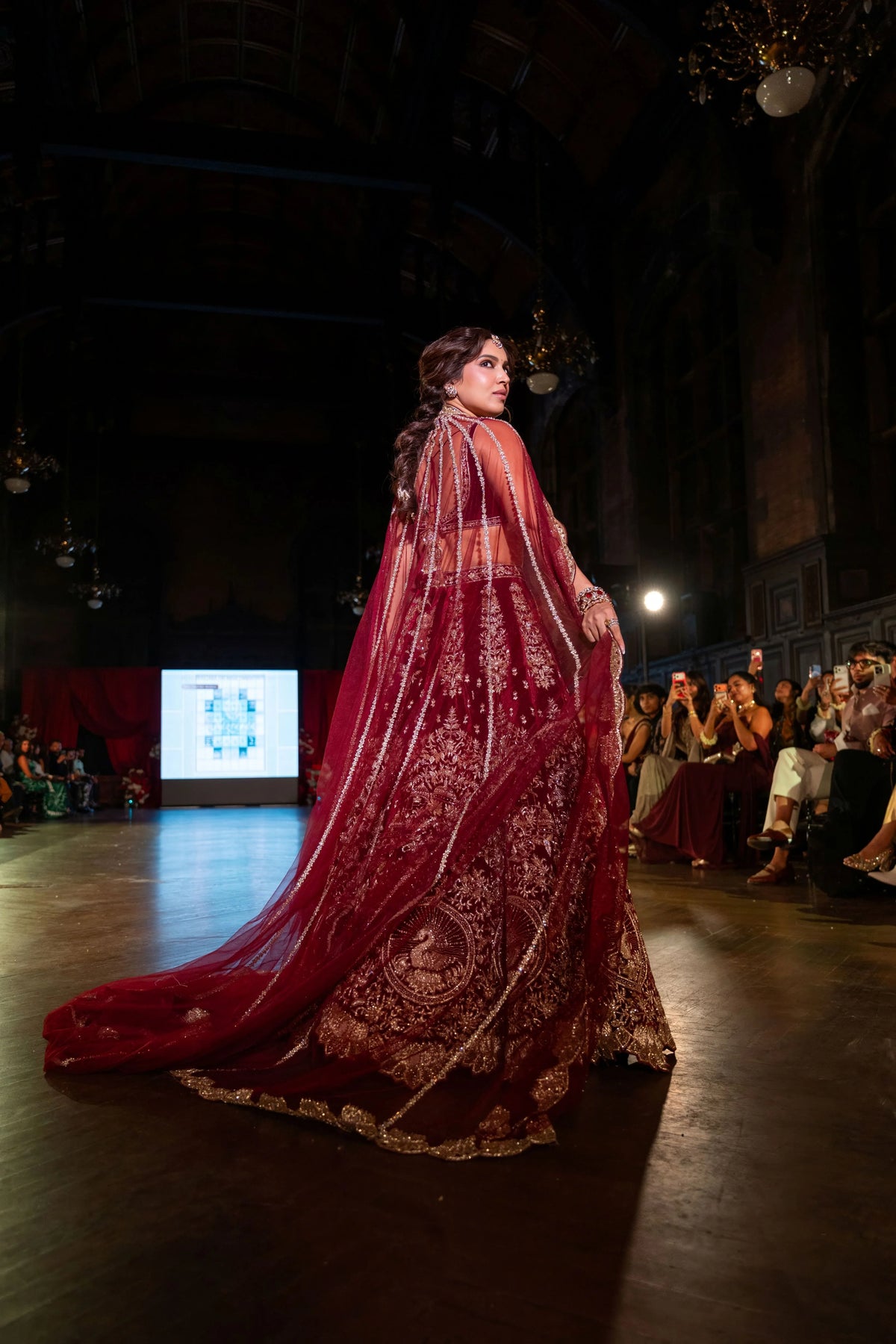 Back view of the Belur Math maroon velvet lehenga with a long red net dupatta trailing on the runway