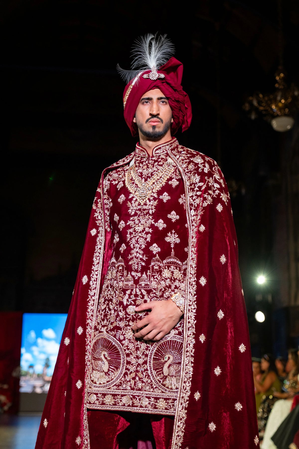 Close front view of the Belur Math maroon velvet sherwani with a gold embroidered medallion and feathered turban