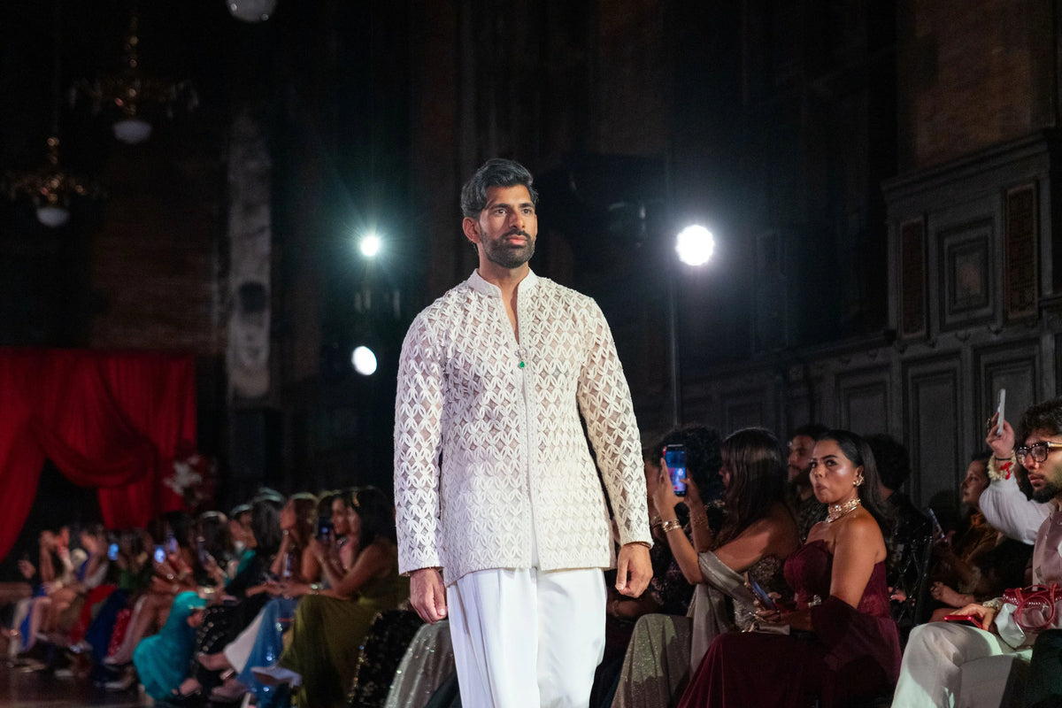 Wide runway view of the Chitrakavya ivory jacket and trousers with seated audience