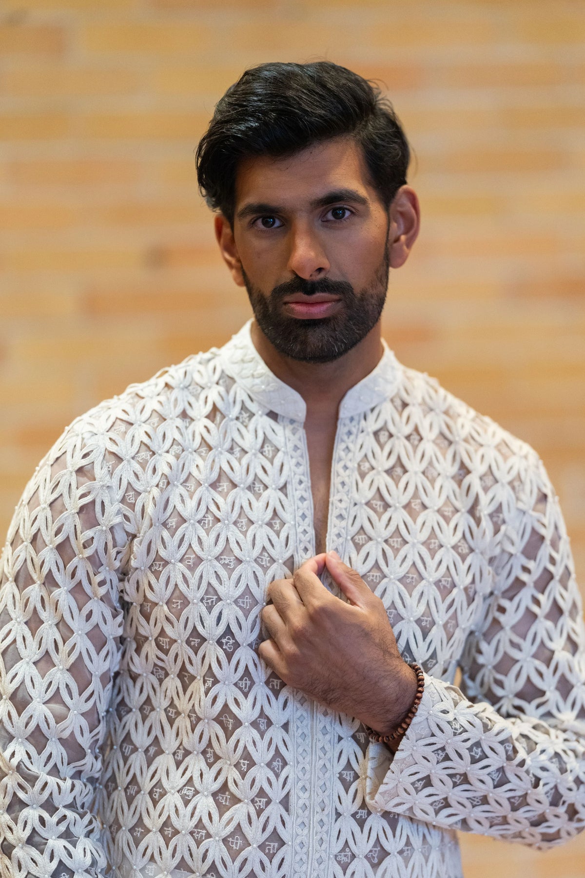 Close portrait of the Chitrakavya ivory lattice jacket and kurta, hand resting on the chest