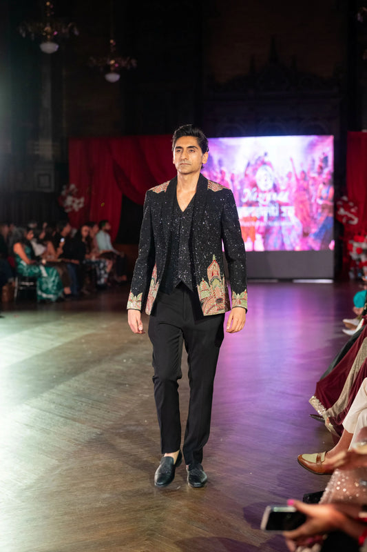 Man walking the runway in the Dakshineshwar Kali black embroidered jacket with black trousers