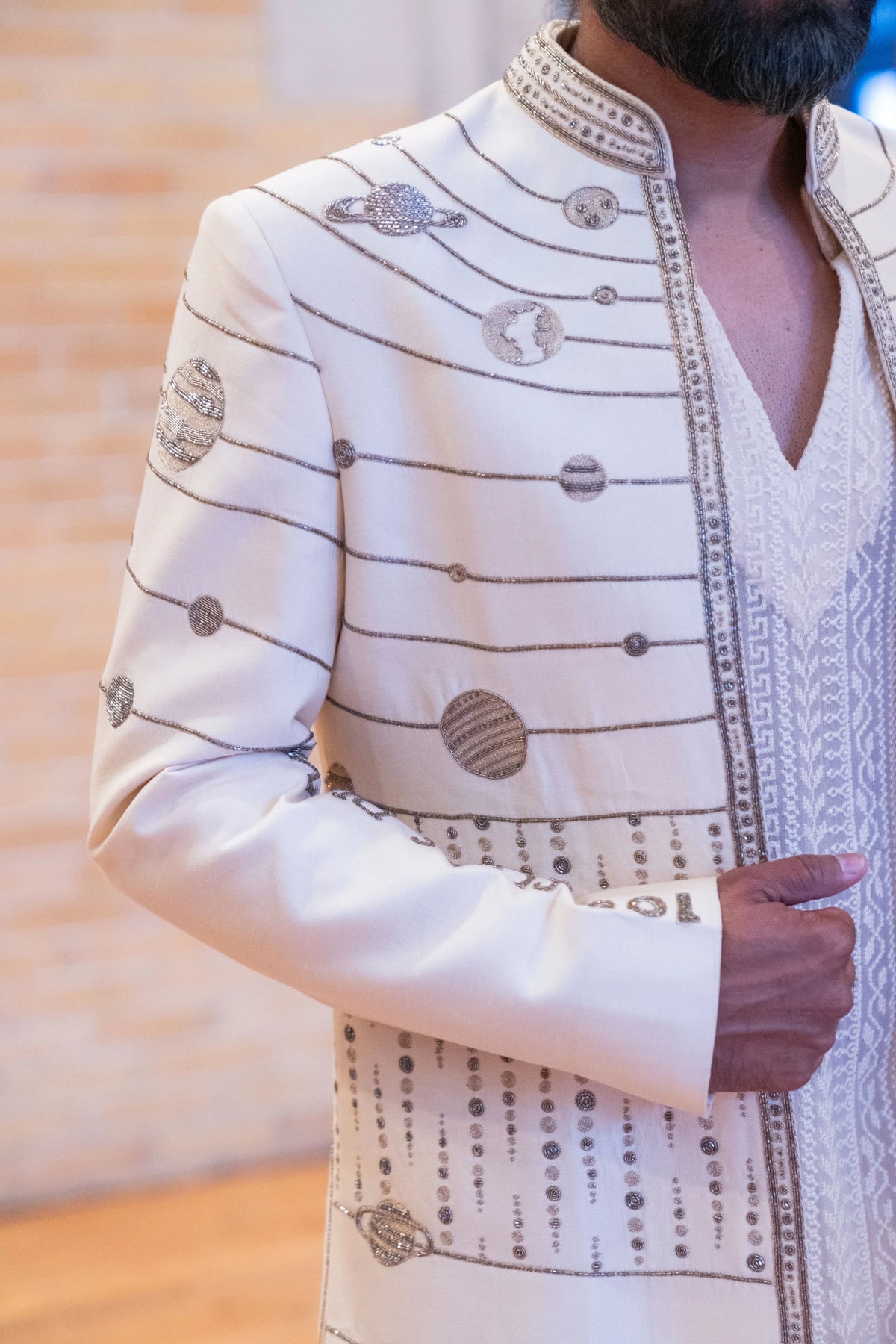 Detail of the embroidered planet discs and orbit lines on the shoulder and lapel of the ivory Hanuman Chalisa jacket