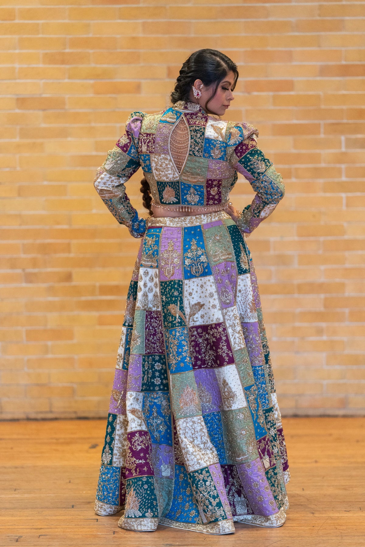 Back view of the Holi patchwork jacket lehenga with puffed shoulders and a patchwork flared skirt against a brick wall