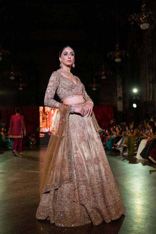 Model on the runway in a Jagannath Puri champagne gold lehenga set with an embroidered blouse and a long gold net dupatta