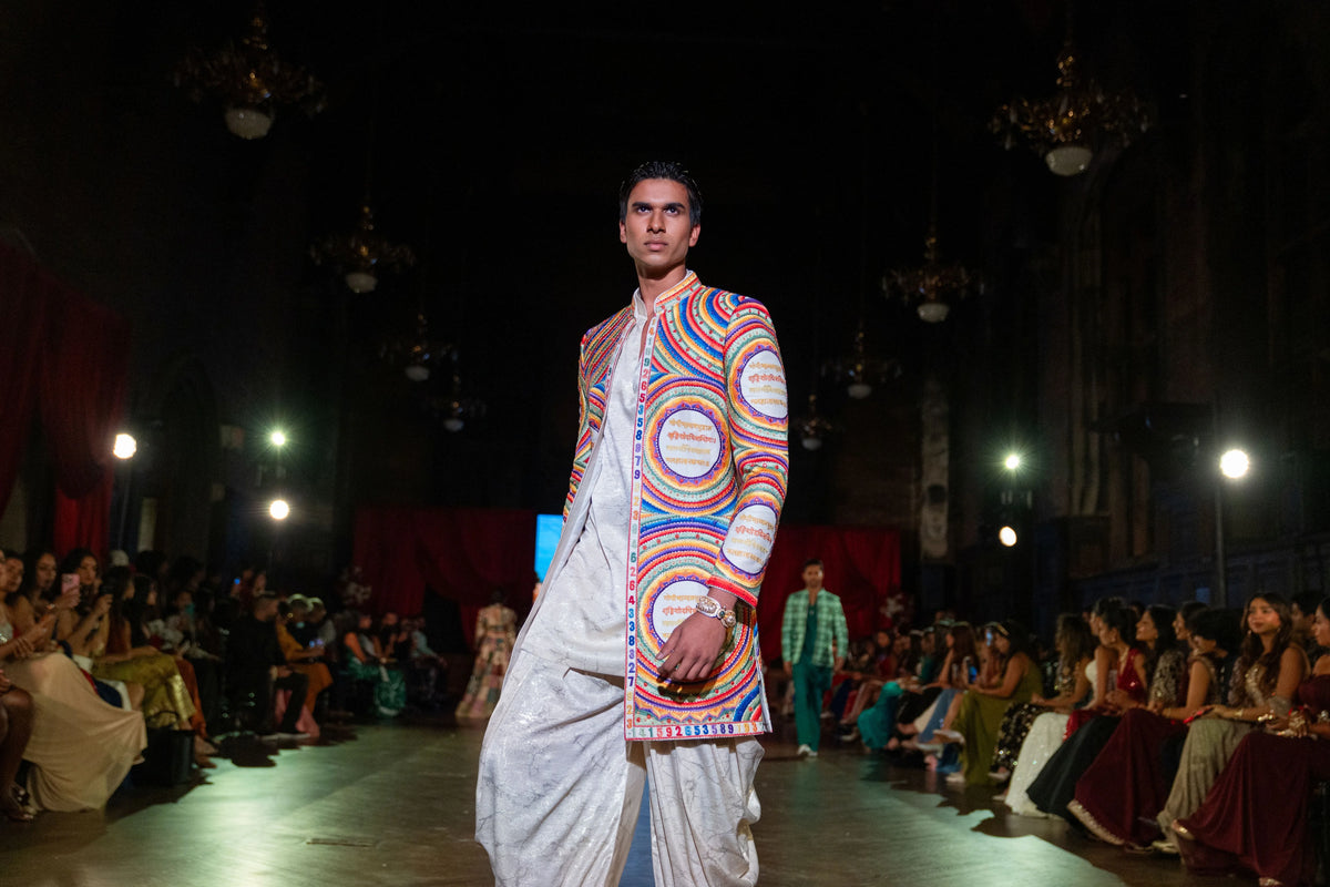 Side-angled distant view of the Katapayadi multicolor jacket and white dhoti pants on the stage