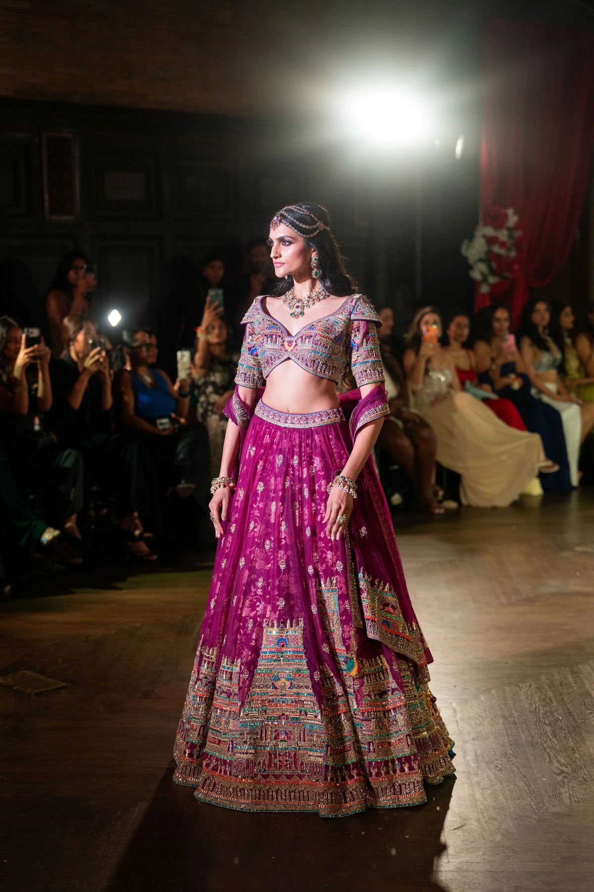 Three-quarter runway view of the Meenakshi Temple magenta lehenga with embroidered cold-shoulder blouse and net dupatta