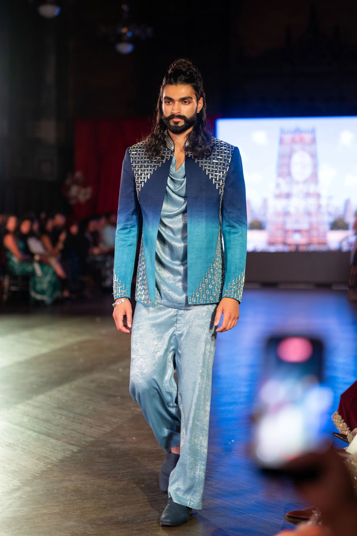 Meru Prastara blue ombre embroidered jacket and pale blue trousers, model striding toward the audience