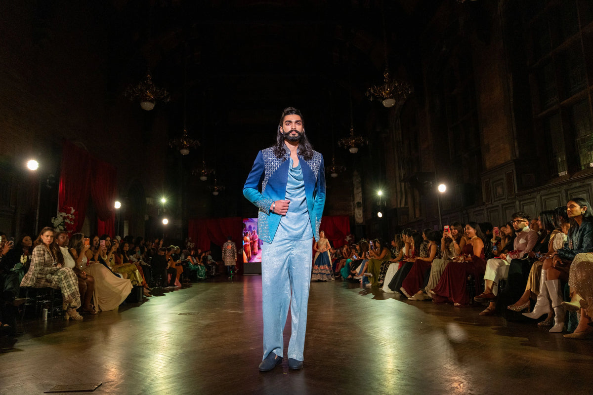 Distant runway view of the Meru Prastara blue ombre jacket and trousers with seated guests