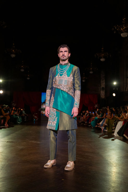 Distant standing view of the Angkor Wat green sherwani, teal sash and green trousers on the stage