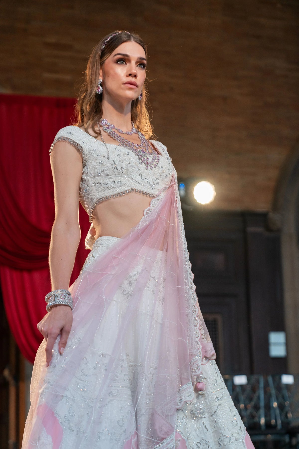 Prem Mandir pale lehenga with a pink dupatta, model with hand on the sheer net and silver jewelry