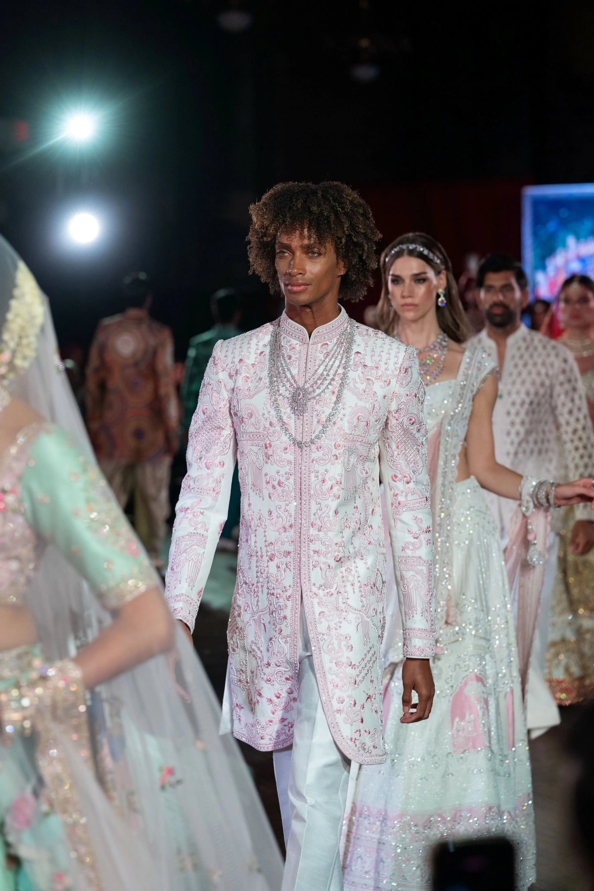 Prem Mandir pale embroidered sherwani with layered pearl chains, model walking toward the camera