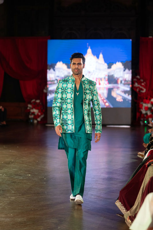 Model in the Sarvatobhadra green geometric-pattern jacket with a teal kurta and trousers, temple image on screen behind