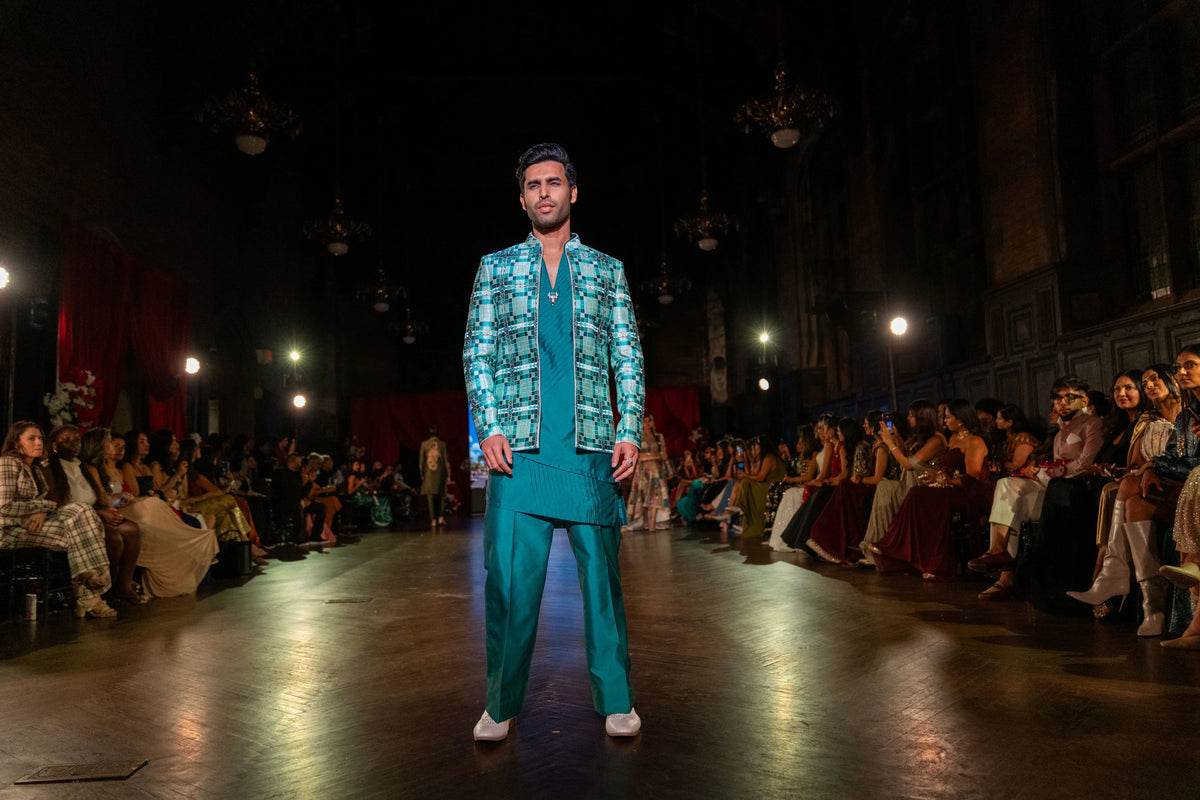 Sarvatobhadra green patterned jacket with teal kurta and trousers mid-stride on the runway