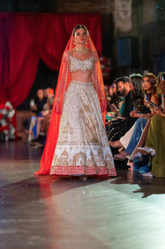 Siddhivinayak ivory and red lehenga with the red net dupatta draped over the head, model walking the runway