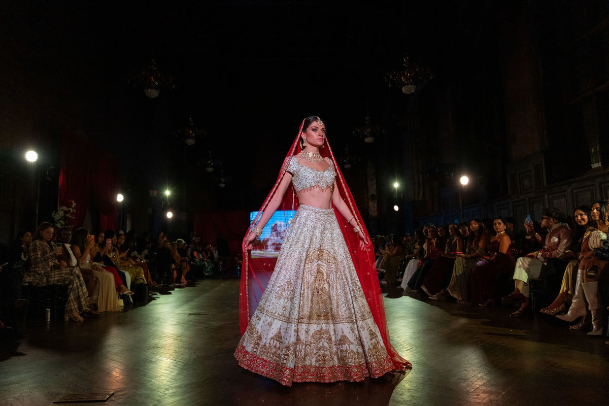 Distant runway view of the Siddhivinayak ivory lehenga with a red dupatta, model standing on the stage
