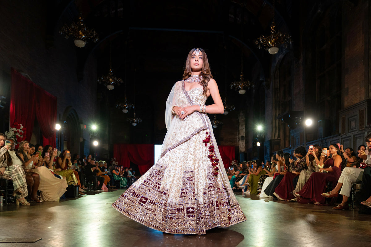 Distant runway view of the Venkateshwara ivory lehenga with a maroon embroidered border
