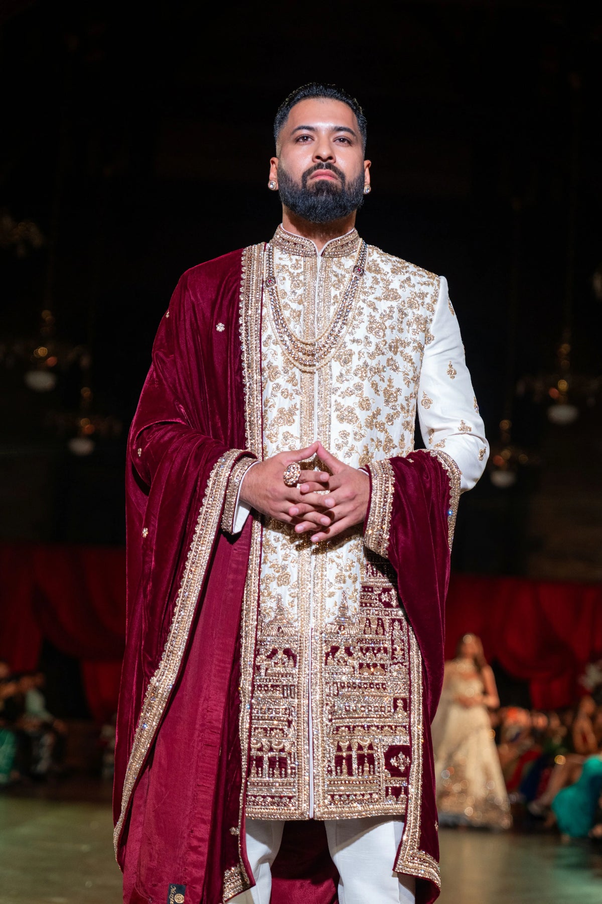 Close front view of the Venkateshwara ivory sherwani with a gold chain and a maroon shawl, hands clasped