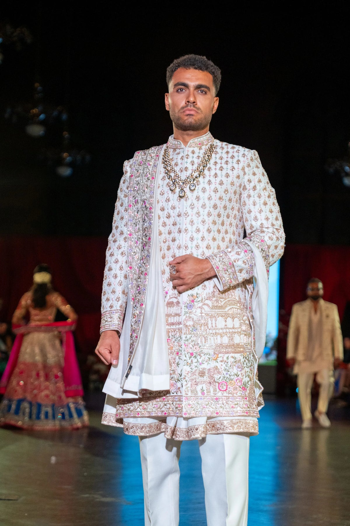 Close front view of the Vrindavan ivory sherwani showing pearl chains and the pink floral embroidered hem