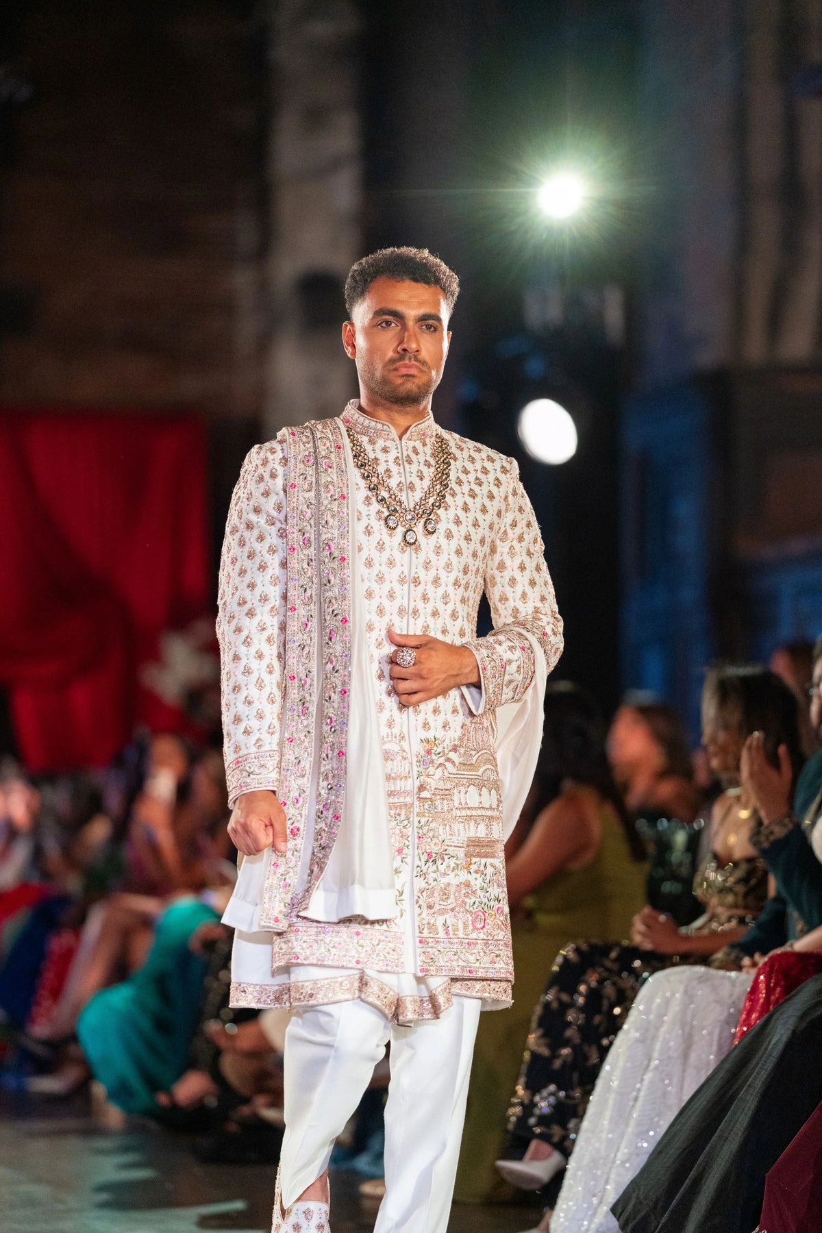 Vrindavan embroidered ivory sherwani with a beaded necklace and hand on the front panel, three-quarter view