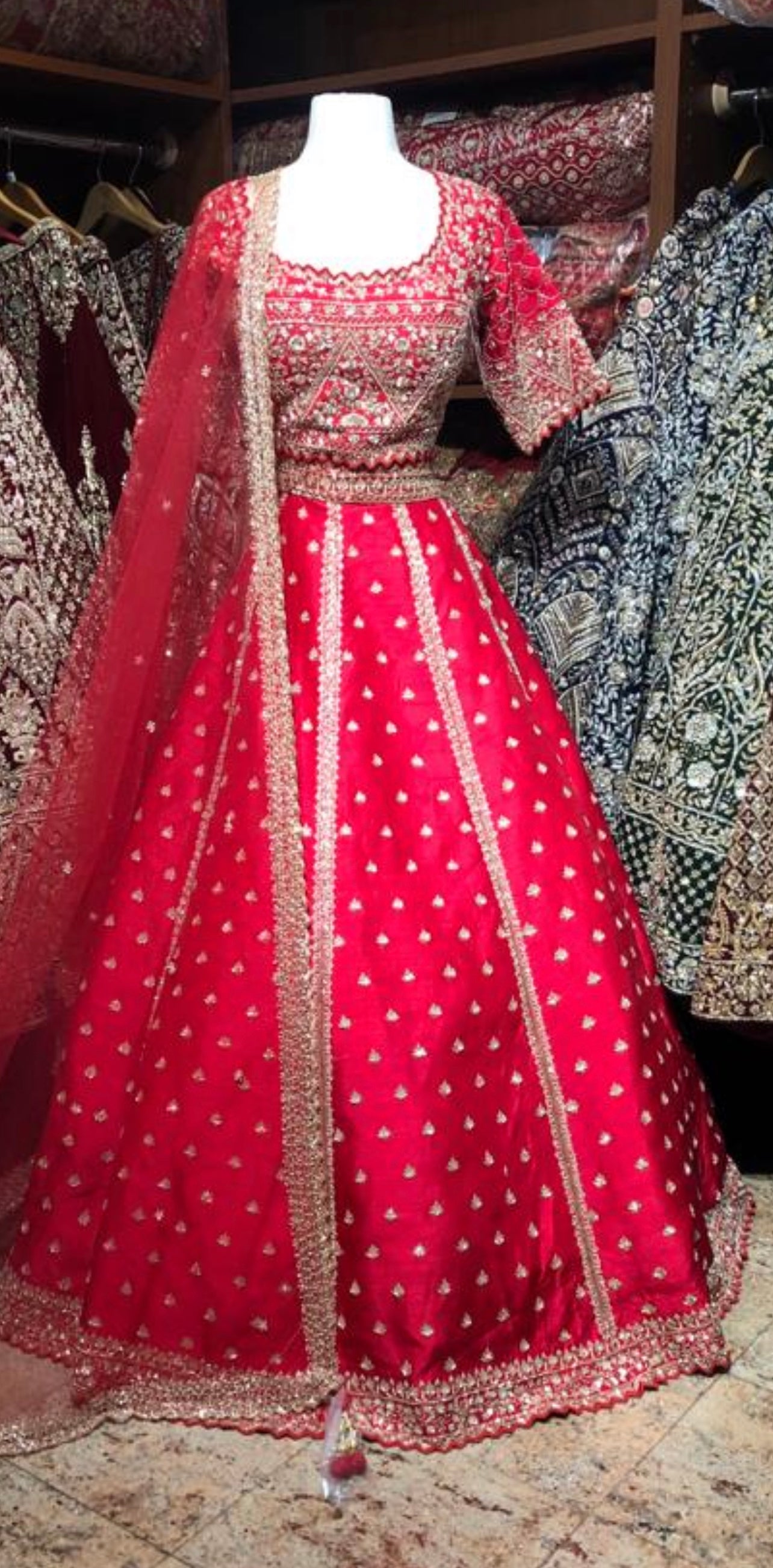 Photo of A bride in a red lehenga laughing with her bridesmaids on her  wedding day